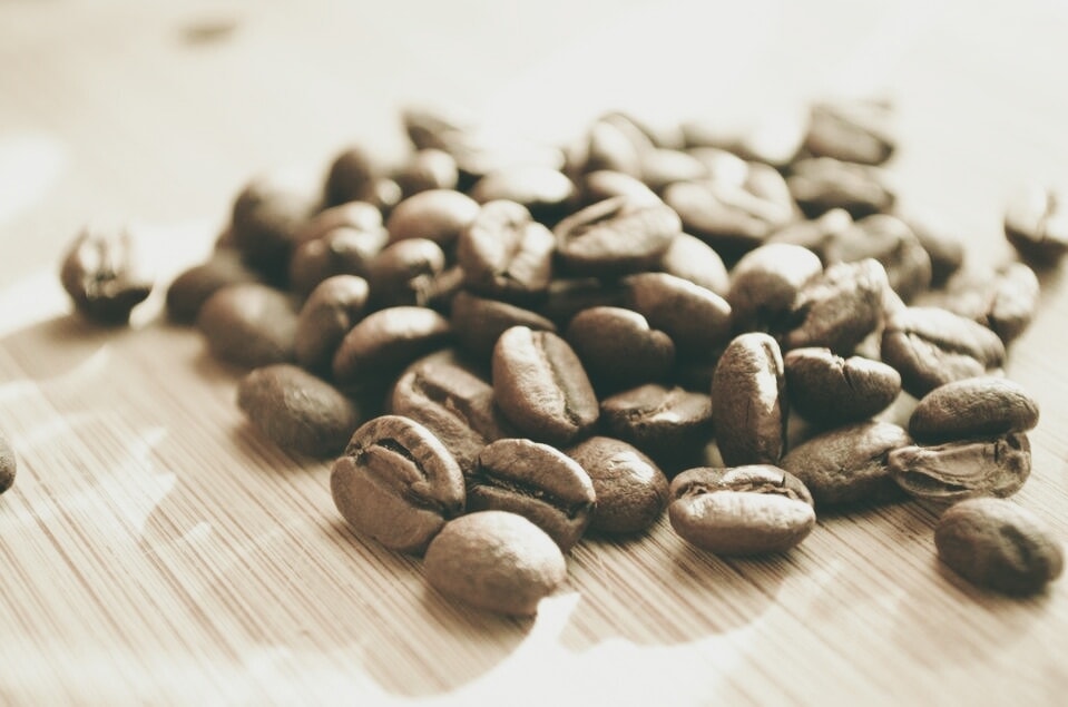 Close-up of coffee beans on a brown wooden surface with soft bokeh, a bright tabletop composition