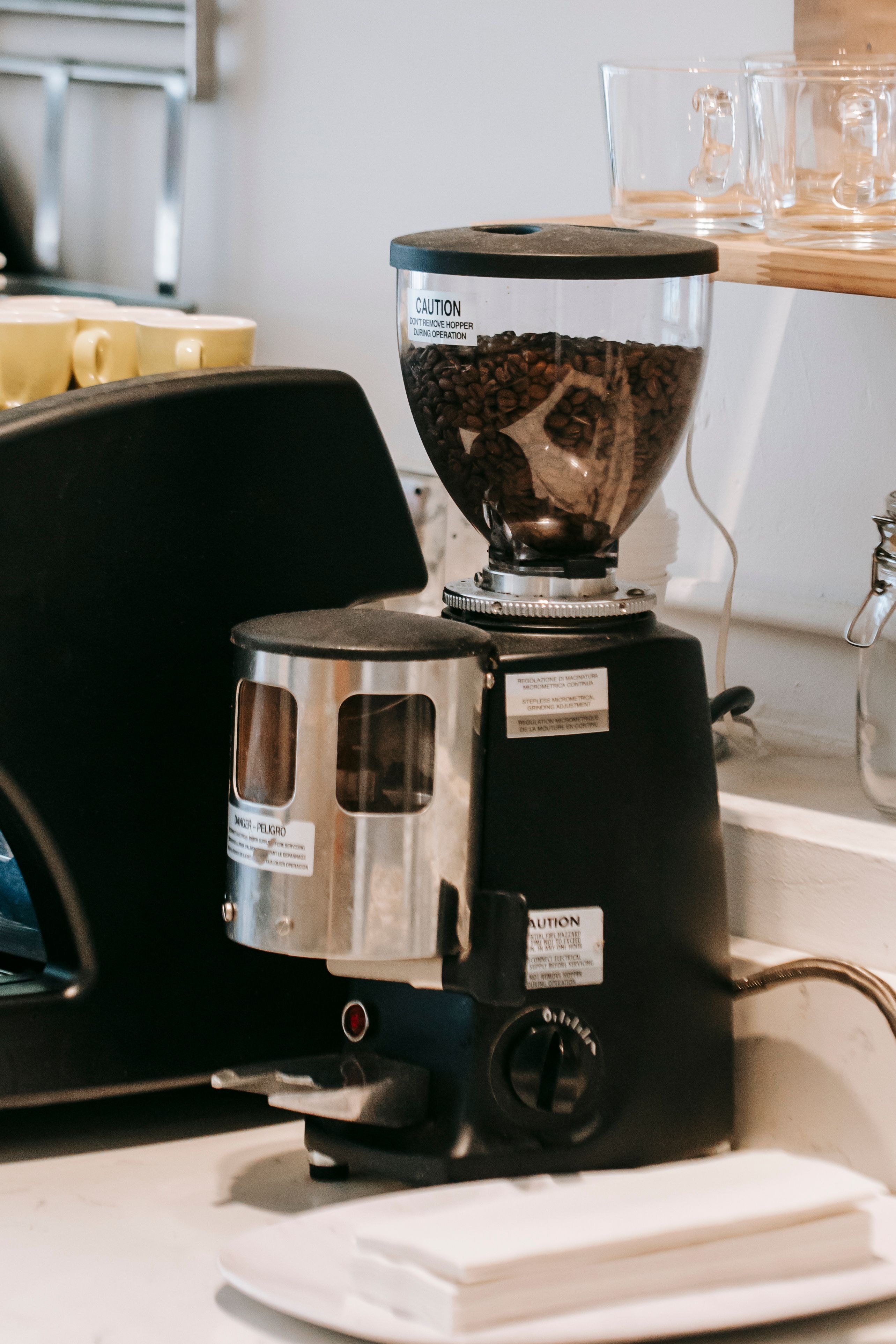 Modern electric coffee burr grinder filled with beans, sitting on a kitchen counter