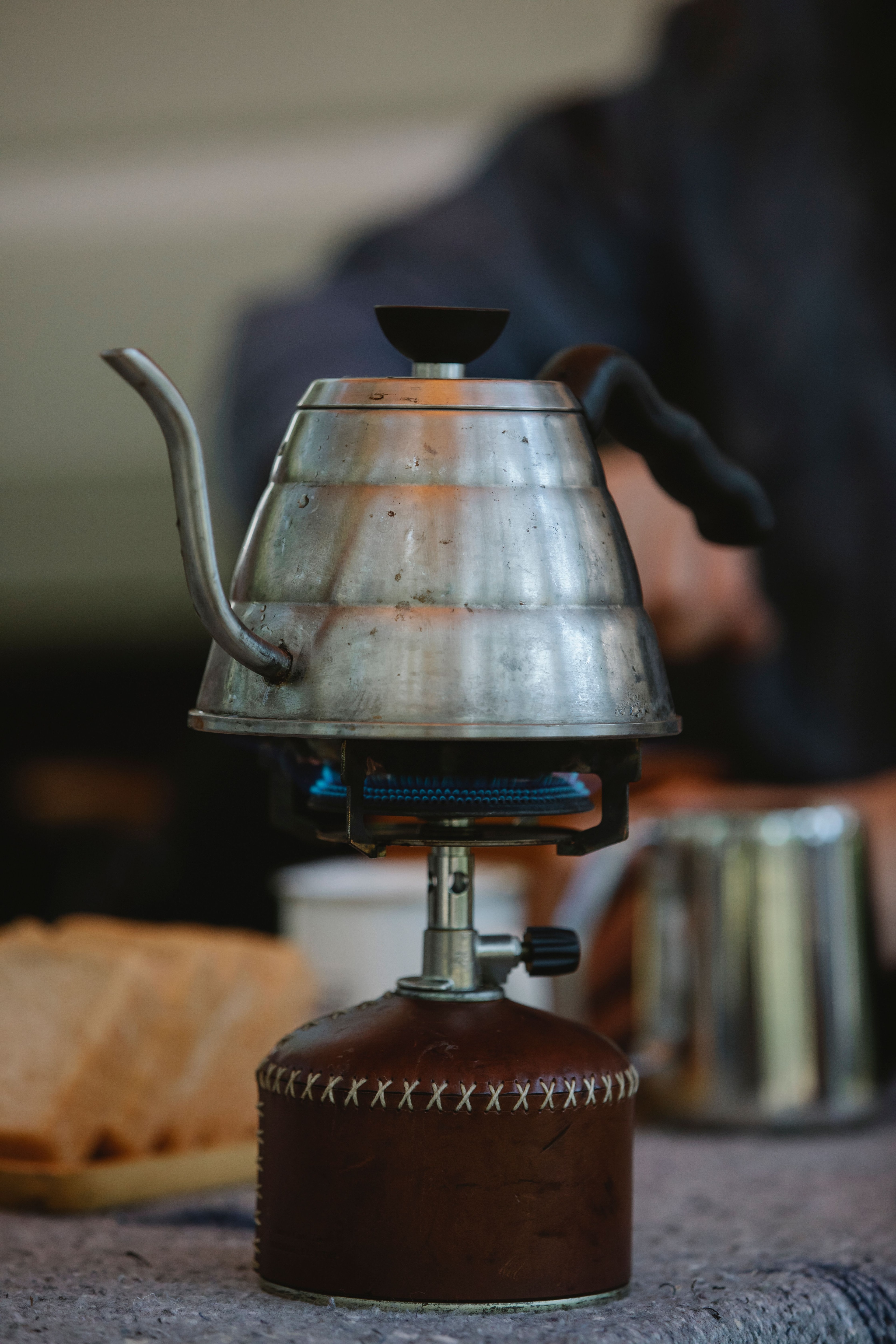 Gooseneck pour-over kettle with a thin curved spout, placed on a portable gas stove