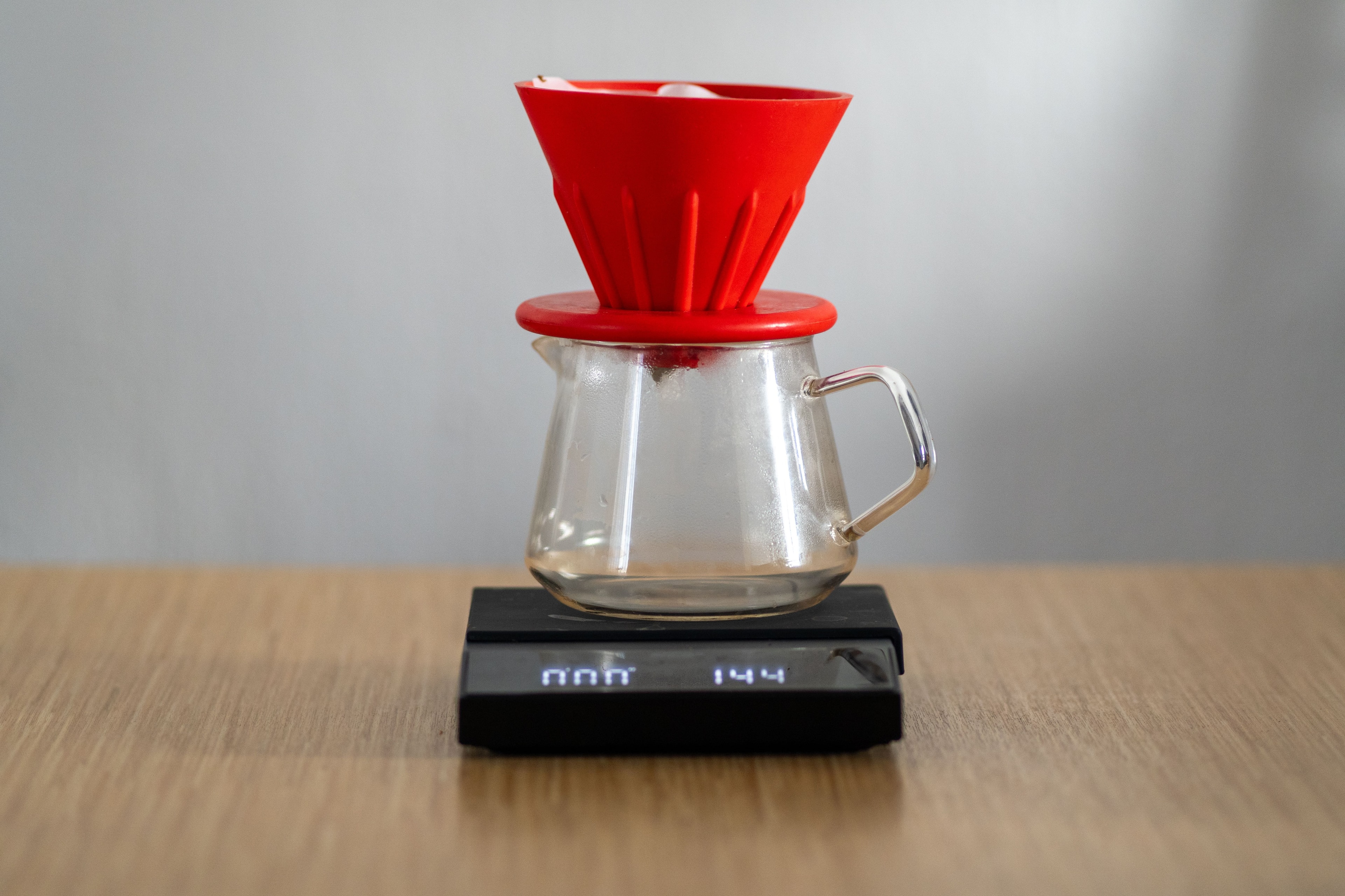 Red V60-style cone pour-over coffee dripper resting on a digital scale