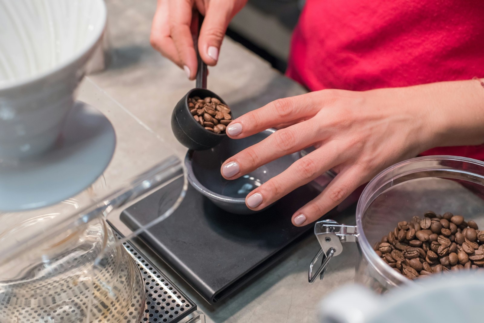 Hands carefully scooping and measuring coffee beans on a scale, conveying craftsmanship and precision